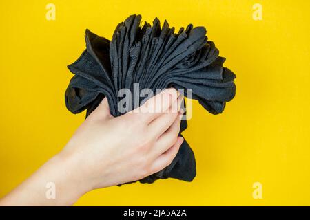 une pile de nouvelles chaussettes noires fraîches à la main sur fond jaune Banque D'Images