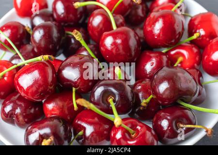 Pile de baies de cerises rouges mûres fraîches sur plaque blanche topview. Nourriture locale biologique Banque D'Images