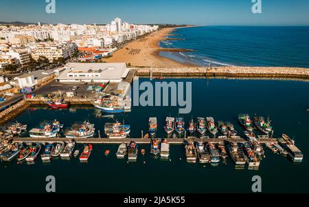 Belles villes aériennes de la ville portugaise touristique de Quarteira. Bateaux de pêche sur le quai en premier plan et touristes bains de soleil en arrière-plan Banque D'Images