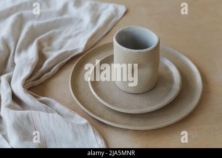 vue sur une table en bois avec une tasse et des assiettes en céramique. ensemble minimaliste de vaisselle en céramique faite à la main et de poterie Banque D'Images