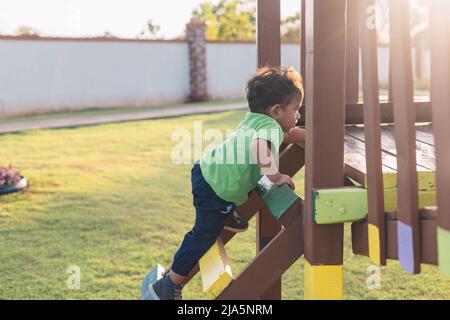 Latino bébé escalade des escaliers en bois, dans le parc Banque D'Images