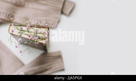 Pull chaud et un livre avec fleurs sur fond blanc. Vintage confortable. Flat lay, vue de dessus Banque D'Images