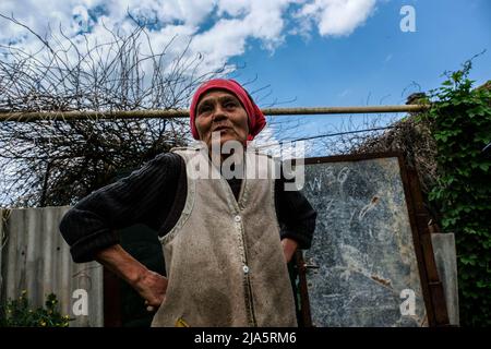 Une femme âgée, Alina, de 76 ans, devant sa maison. Siversk est une ville de 11 000 habitants connue pour son usine de briques, située dans la région de Donetsk. À l'heure actuelle, de nombreuses personnes ont évacué la ville fantôme en raison de sa proximité avec la ligne de front qui se rapproche chaque jour. Les quelques personnes qui vivent encore dans la ville ont leurs maisons sans eau, gaz et électricité. Banque D'Images