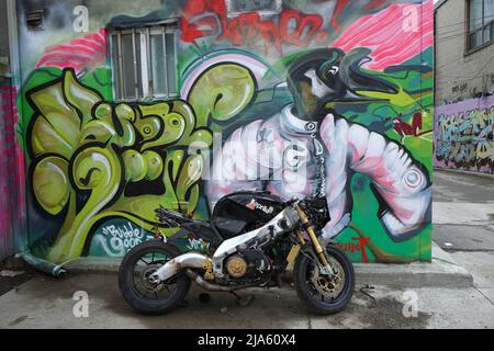 Toronto (Ontario), Canada - le 27 mai 2022 : une moto d'époque est garée devant un tableau mural coloré sur une maison de Mews dans un vieux quartier Banque D'Images