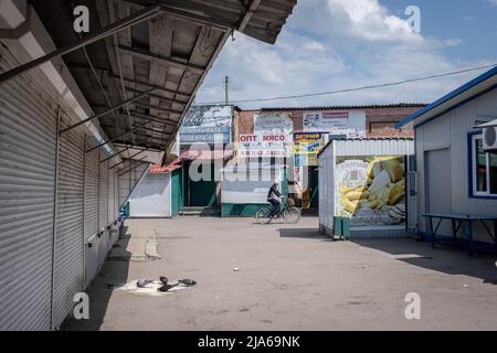 Bakhmut, Ukraine. 24th mai 2022. Un homme avec le vélo passe devant le marché vide à Bakhmut, Donbas. Comme Bakhmut est une ville clé des forces ukrainiennes pour défendre la région du Donetsk (Donbass), la ville est attaquée par les troupes russes. L'invasion russe de l'Ukraine a commencé le 24 février, la guerre qui a tué de nombreux civils et soldats. Crédit : SOPA Images Limited/Alamy Live News Banque D'Images