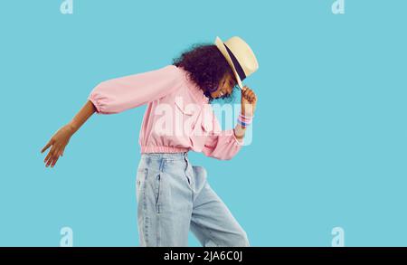 Joyeux enfant afro-américain en vêtements d'été dansant isolé sur fond bleu Banque D'Images