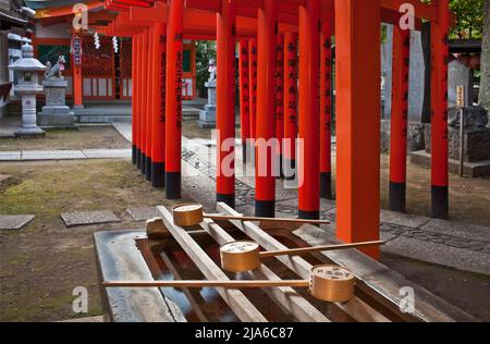 Chōzubachi bassin purifiant et rangées de portes de torii au sanctuaire Toyosakainari à Shibuya, Tokyo, Japon Banque D'Images