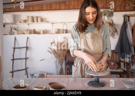 femme caucasienne potter travaillant avec de l'argile sur une roue de potier dans un studio professionnel créatif, artiste féminine créant la poterie artisanale faite à la main. Détendez-vous Banque D'Images