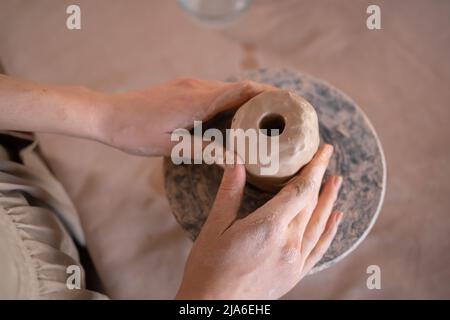 main de femme créative sculptant de l'argile brute sur une roue de potier, façonnant un bol dans un atelier de poterie pendant une classe de maître ou d'atelier. la formation de Banque D'Images