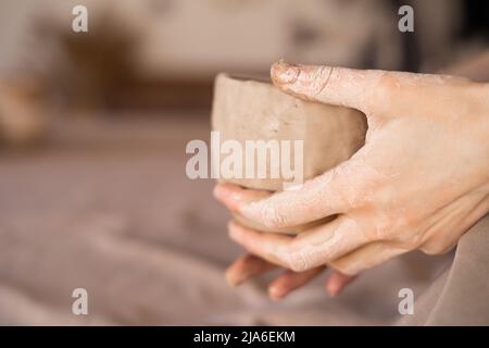 Potter au travail. Les mains de Potter dans l'argile forment un pot dans un cercle. Gros plan de la femelle sculptant des bols de l'argile humide crue. Banque D'Images