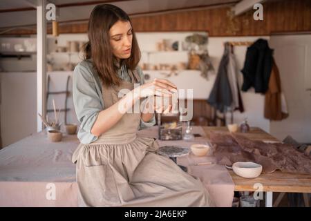 un jeune artisan s'est concentré sur la sculpture d'un bol en argile brute lors d'un cours de poterie ou d'un atelier dans un studio créatif. Femme céramique propriétaire d'affaires de fabrication Banque D'Images