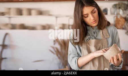 Un jeune artisan s'est concentré sur la sculpture d'un bol en argile brute lors d'un cours de poterie dans un studio créatif. Une femme propriétaire d'entreprise de céramique fait de l'artisanat pour Banque D'Images