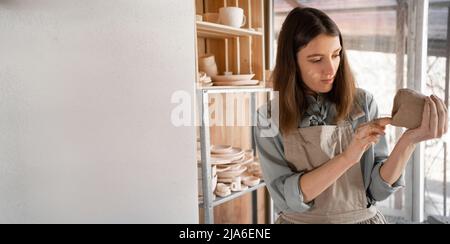 Un jeune artisan s'est concentré sur la sculpture d'une carafe d'argile brute lors d'un cours de poterie ou d'un atelier dans un studio créatif. Un jeune céramiste est engagé Banque D'Images