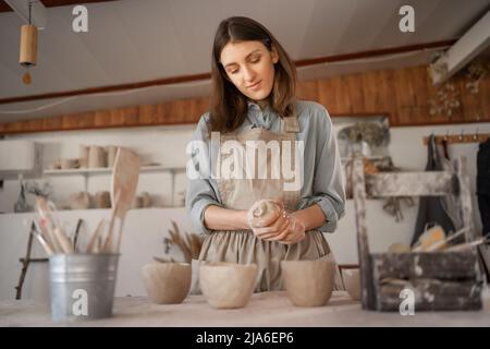 les femmes artisanales se sont concentrées sur la carafe à modeler de l'argile brute tout en cours de poterie ou atelier en studio créatif. Femme céramique propriétaire d'affaires de fabrication Banque D'Images