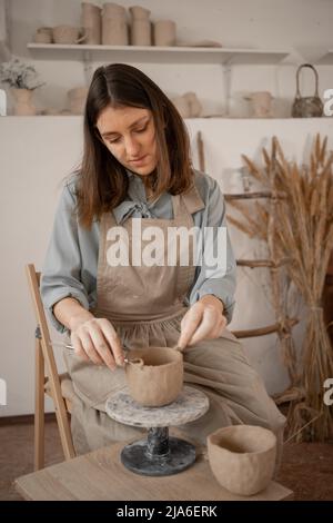 Un jeune artisan s'est concentré sur la sculpture d'un bol en argile brute tout en faisant de la poterie dans un studio créatif. Femme céramique propriétaire d'affaires de fabrication d'artisanat à la vente Banque D'Images