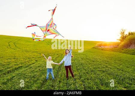 Des enfants heureux lancent un cerf-volant sur le terrain. Petit garçon et fille en vacances d'été. Banque D'Images