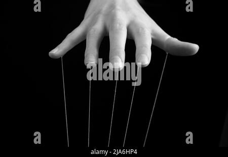 Main de femme avec cordes sur les doigts. Influence, manipulation, abus, concept de domination. Noir et blanc. Photo de haute qualité Banque D'Images