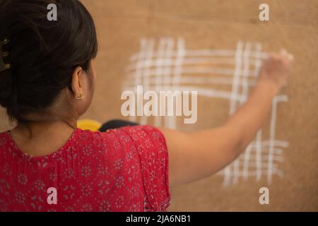 Femme indienne dessinant des rangoli Kolam sur terre Banque D'Images