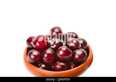 Cerises dans un bol en argile isolé sur fond blanc. Place pour votre texte. Banque D'Images