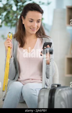 brunette femme mesurant ses bagages de cabine avant de partir en vacances Banque D'Images