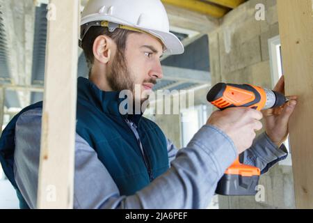 un constructeur forant des trous sur le mur Banque D'Images