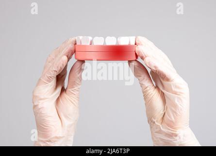 Mains dans des gants tenant le modèle de mâchoire avec point rouge. Inflammation des gencives, traitement des maladies parodontales. Dentisterie, concept d'hygiène buccale. Photo de haute qualité Banque D'Images