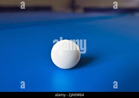 Une balle de tennis blanche sur une table bleue avec le reflet. Ping pong, jeux de sport de table. Banque D'Images