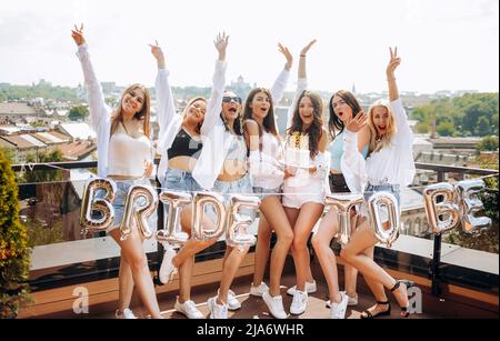 Un groupe de femmes heureuses et gaies dansant ensemble et s'amusant sur le toit à la maison. Fête de la Bachelorette. Banque D'Images