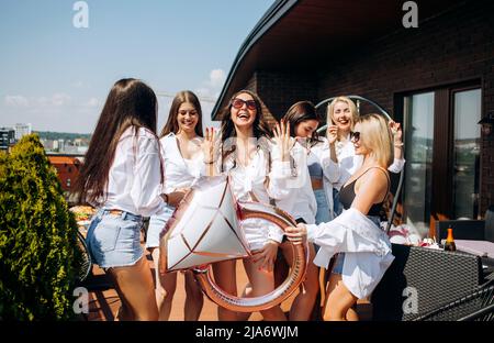 Un groupe de femmes heureuses et gaies dansant ensemble et s'amusant sur le toit à la maison. Fête de la Bachelorette. Banque D'Images