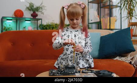Petite fille enfant de réparer la pièce de technologie de carte-mère d'ordinateur, en utilisant la loupe à la maison Banque D'Images