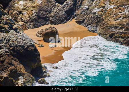Plage sur l'océan avec plage de sable entourée de rochers Banque D'Images