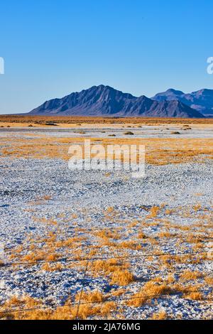 Les montagnes noires entourent le paysage du désert de sable blanc Banque D'Images