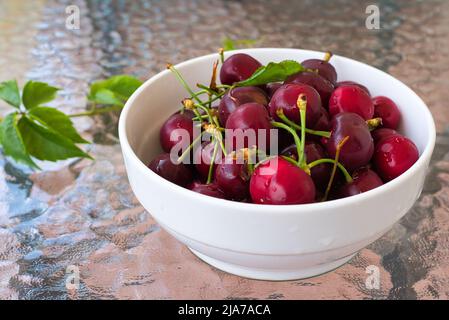 Cerises douces rouges fraîches, dans un panier en osier sur fond de bois Banque D'Images