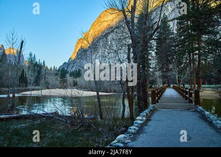 Sentier de randonnée menant au pont sur la rivière de Yosemite avec des montagnes dorées Banque D'Images