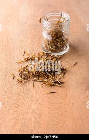 tas de graines de fleurs marigold, longues, minces et pointues arrachent les graines de la base de fleurs séchées pour croître de façon organique avec une bouteille de verre Banque D'Images