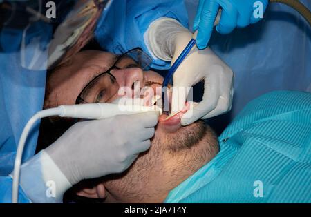 Un homme avec une barbe légère subissant une procédure dentaire Banque D'Images