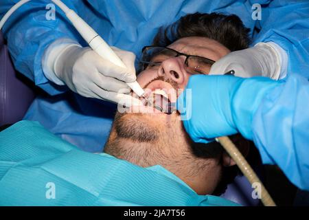 Un homme avec une barbe légère subissant une procédure dentaire Banque D'Images