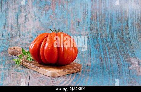 Raf frais coeur de boeuf tomates sur fond bleu, concept rustique, photo Banque D'Images