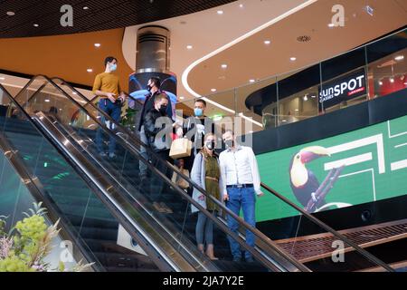 Budapest, Hongrie - 20 novembre 2021: Les jeunes dans les masques du visage en raison de la coronavirus danger restrictions descendre l'escalier dans un grand centre commercial Banque D'Images