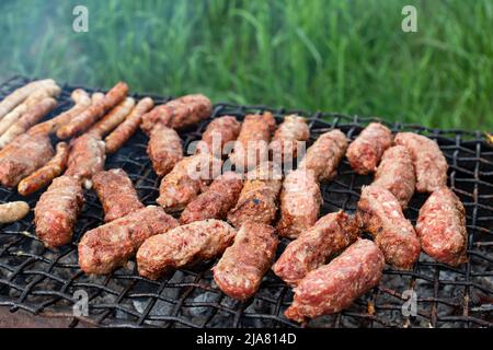 Barbecue chaud de style roumain avec 'Mititei ou mici', cuisine traditionnelle de pique-nique. Banque D'Images