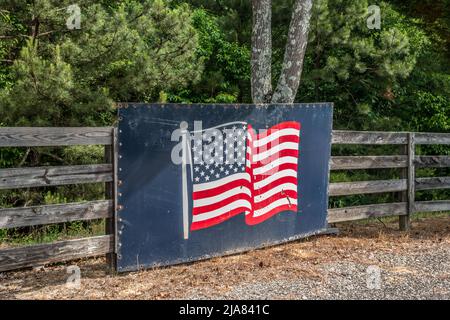 Drapeau américain peint sur un grand morceau de métal boulonné à une clôture extérieure le long de la route montrant le patriotisme et le soutien Banque D'Images