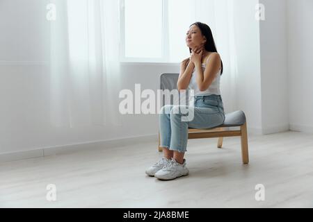 Mal de gorge ganglions lymphatiques enflés. Triste souffrance bronzée belle jeune femme asiatique toucher cou gorge à la maison intérieur salon. Blessures faibles Banque D'Images