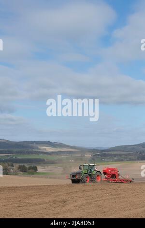 Un tracteur vert Fendt et un semoir Red Horsch plantant un champ labouré au printemps avec une vue sur un paysage agricole pittoresque à Aberdeenshire Banque D'Images