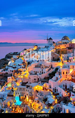 Célèbre site grec emblématique de selfie destination touristique village Oia avec maisons blanches traditionnelles et moulins à vent dans l'île de Santorini dans le bleu du soir ho Banque D'Images