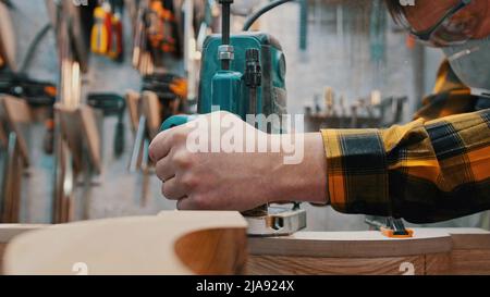 Menuiserie à l'intérieur - un ouvrier du bois polit les détails en bois dans l'atelier Banque D'Images