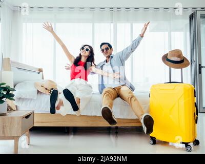 Prêt à voyager, joyeuses vacances, enregistrement. Concept de vacances d'été. Couple asiatique levant les mains avec joie, homme et femme portent des lunettes de soleil sourire avec heureux Banque D'Images