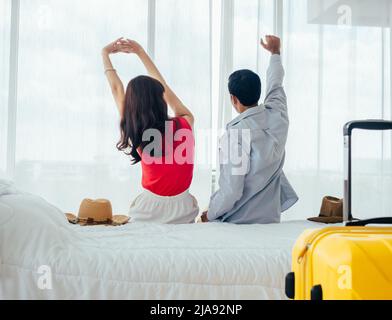 Couple de touristes, de joyeuses vacances. Vacances d'été. Portrait de la vue arrière de jeune asiatique homme et femme s'étirant avec détente sur lit blanc avec costume Banque D'Images