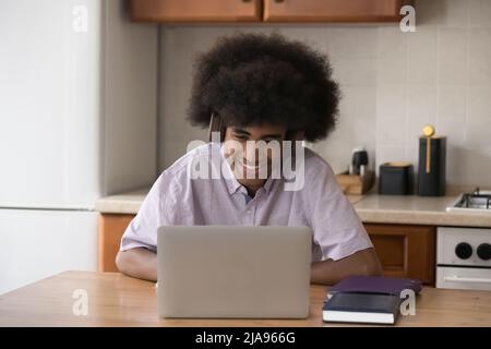Joyeux étudiant gars avec une coiffure rétro africaine à l'aide d'un ordinateur portable Banque D'Images