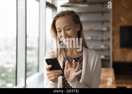 Bonne jolie blonde jeune femme lisant un message texte sur smartphone Banque D'Images