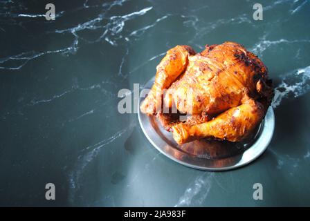 Poulet grillé épicé et juteux de l'Empire Restaurant placé sur une assiette argentée et prêt à déguster Banque D'Images